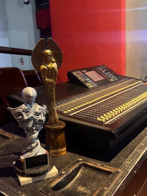 Consola digital de sonido en el teatro, junto a dos premios de las artes escénicas.